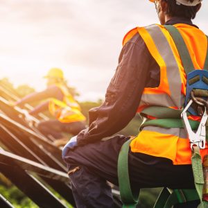 [safety body construction] Working at height equipment. Fall arrestor device for worker with hooks for safety body harness on selective focus. Worker as in construction background.